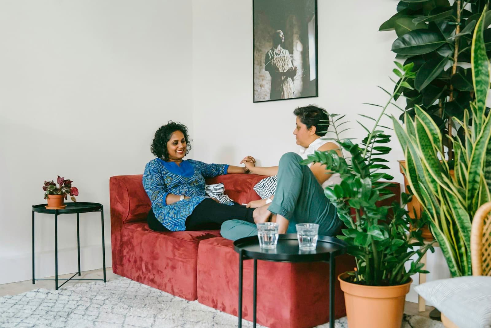 Two women chatting and relaxing together on a sofa at home