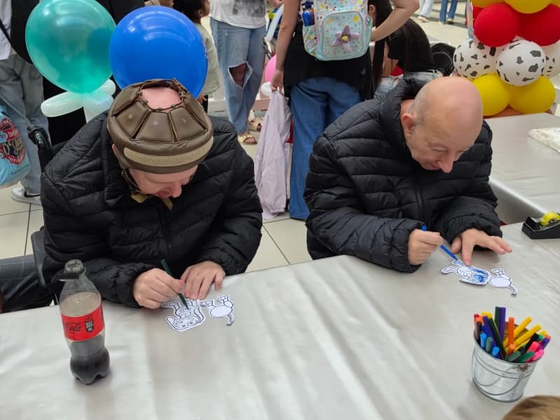 Two men concentrating on colouring in pictures at a table