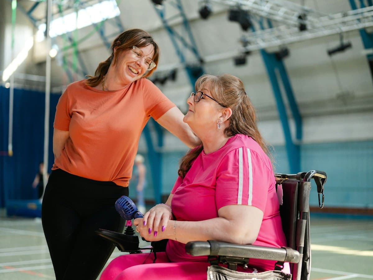 A support worker sharing a laugh with a woman in a wheelchair